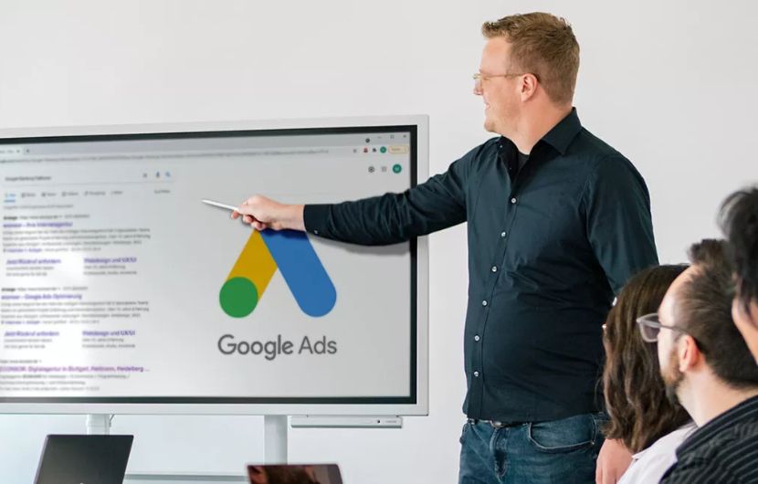 ine Person präsentiert Google Ads Strategien vor einem großen Bildschirm in einem modernen Arbeitsumfeld, unterstützt durch sichtbare Zertifikate und Auszeichnungen – unterstreicht die Kompetenz einer zertifizierten Google-Ads SEA-Agentur.